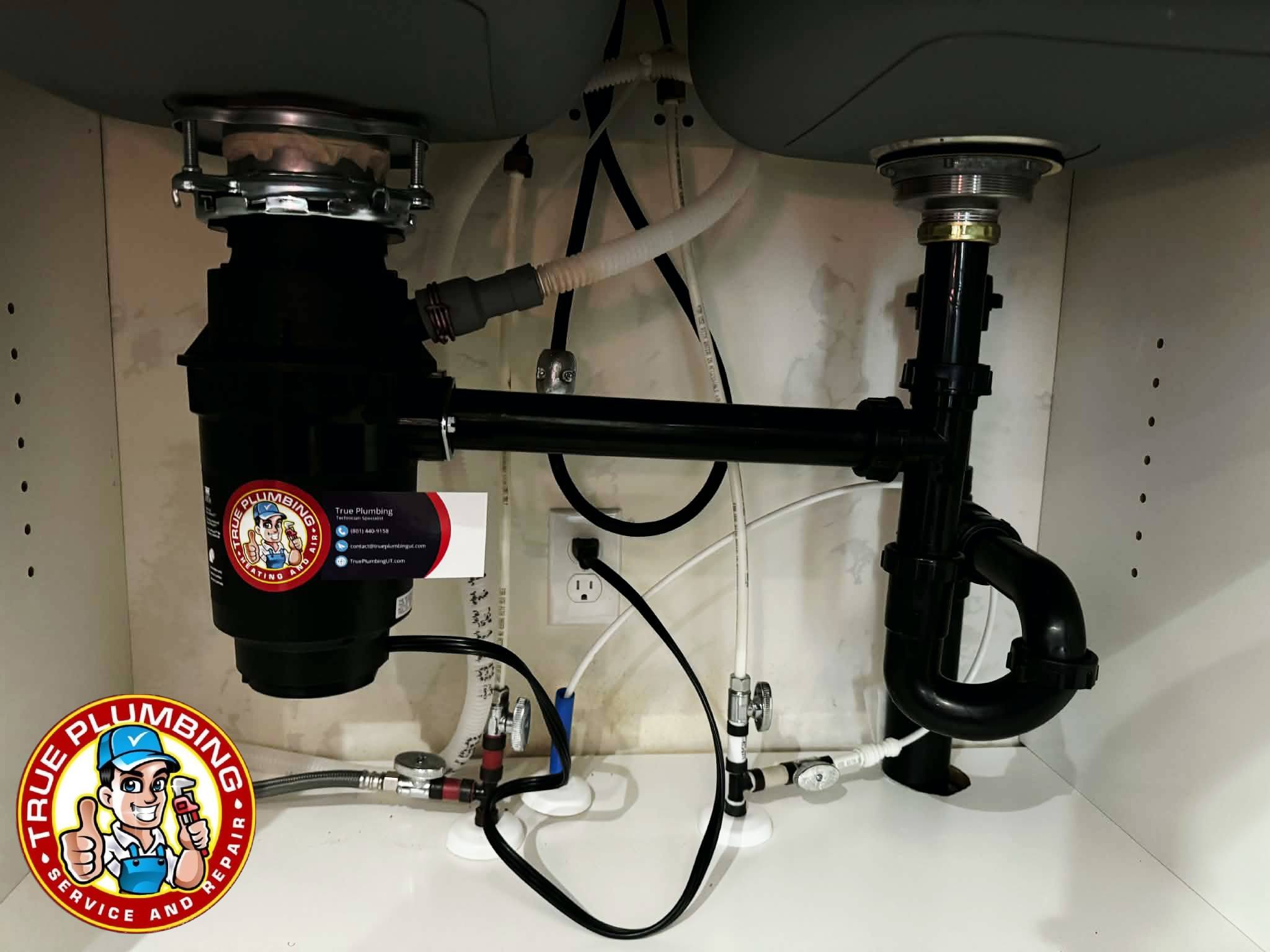 Garbage disposal replacement installed under kitchen sink by plumber connecting new disposal unit and drain plumbing